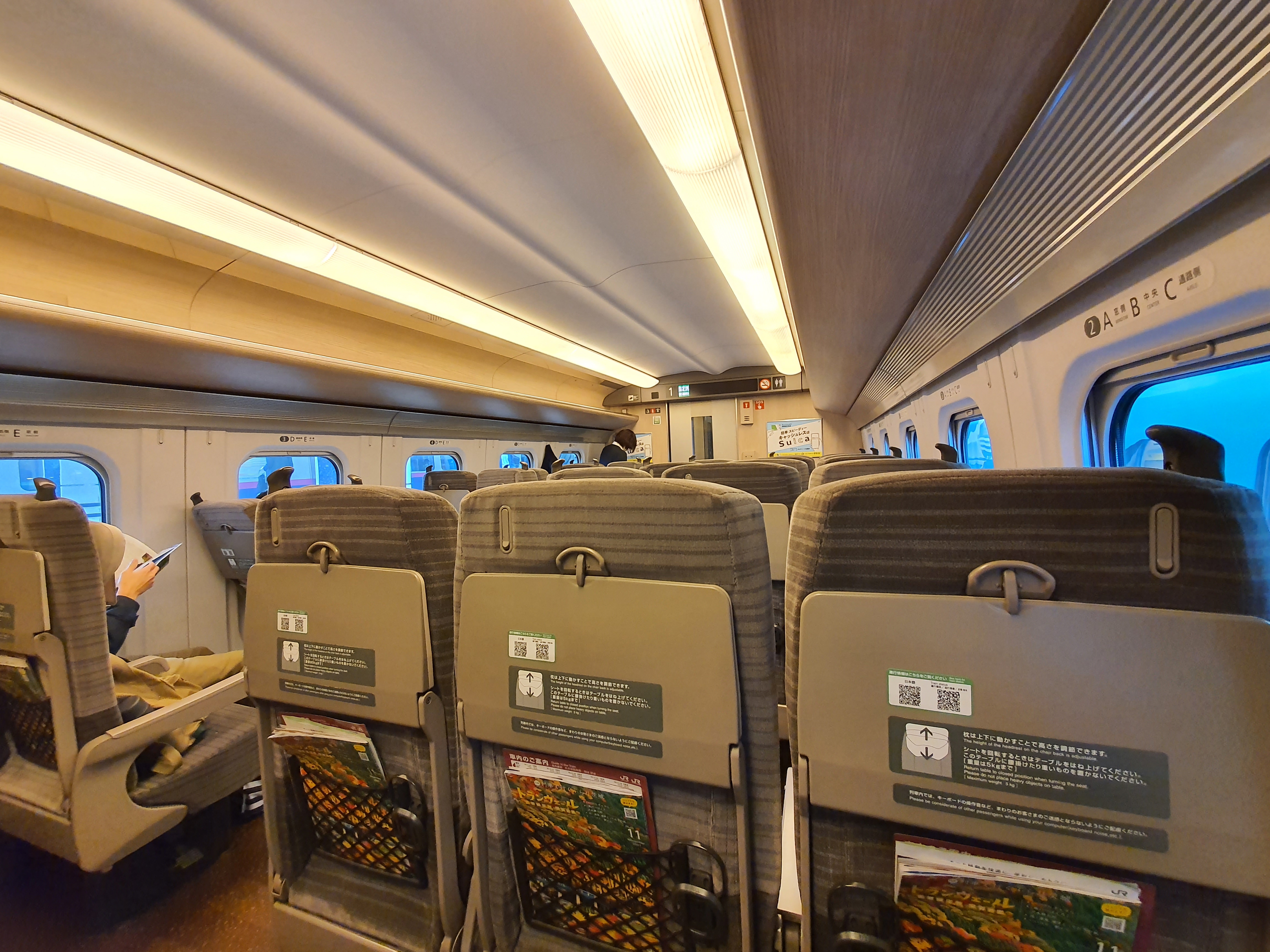 Đoàn tàu Shinkansen E5 Hayabusa màu xanh lá cây và hồng đang đỗ tại sân ga Tokyo hiện đại.