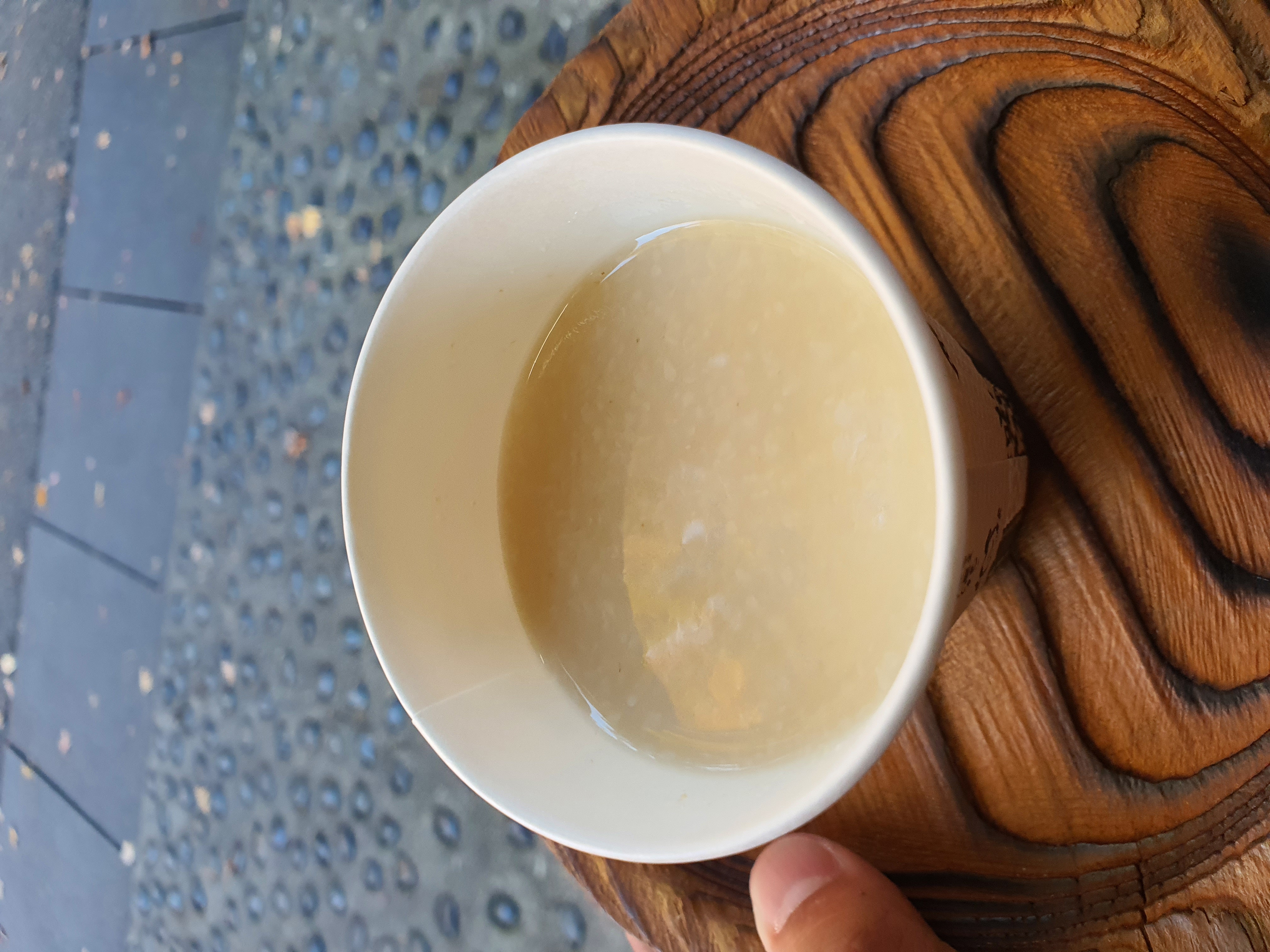 Ly rượu ngọt ấm nóng Amazake màu trắng sữa tỏa khói nhẹ trong tay