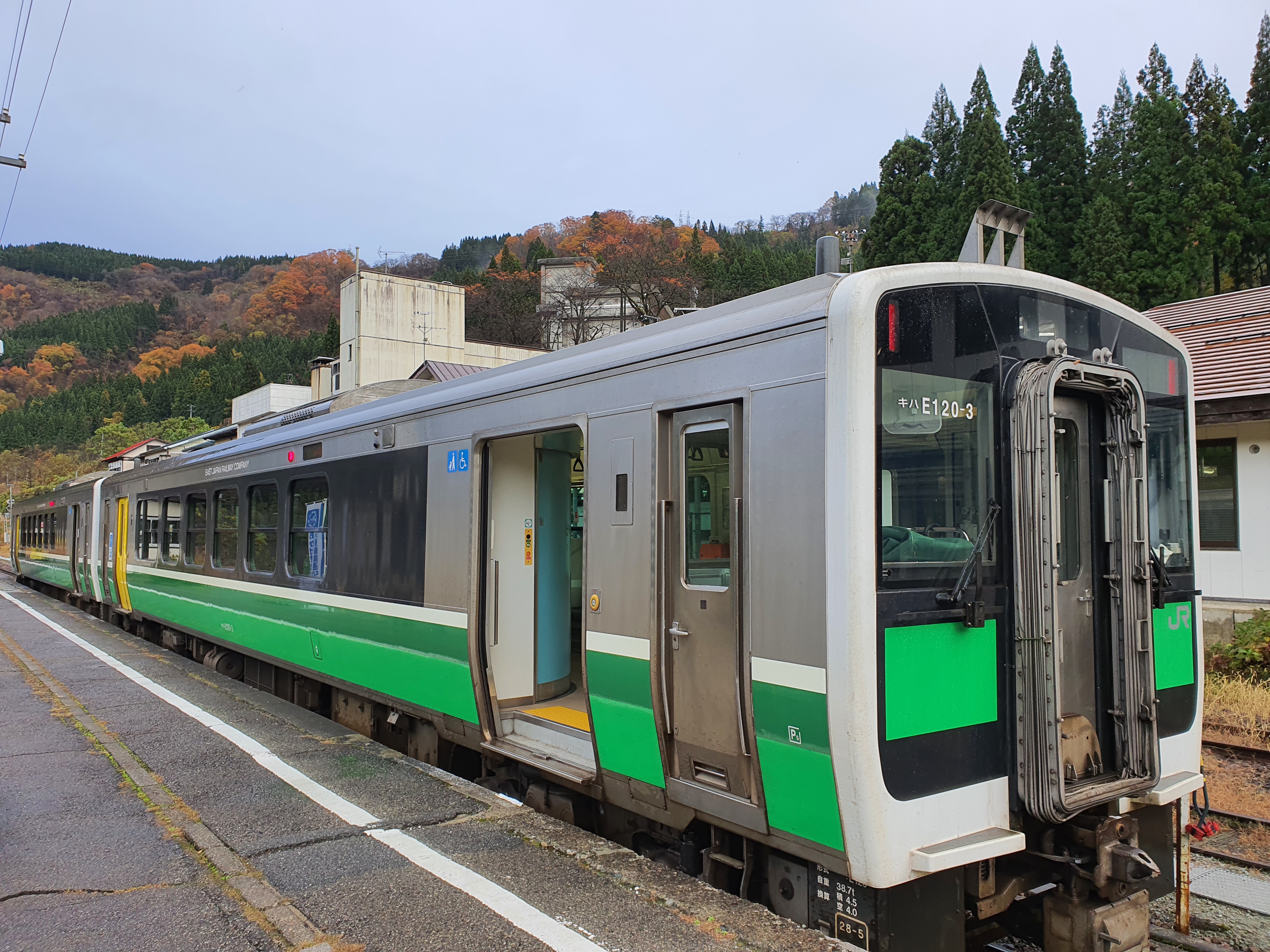 Đoàn tàu địa phương Tadami Line màu xanh lá cây và trắng đậu tại sân ga